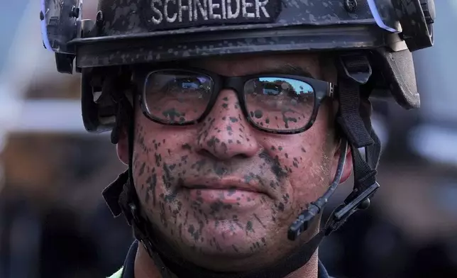 A police officer's face is covered in pepper spray outside the metropolitan detention center of downtown Los Angeles, Sunday, June 8, 2025, following last night's immigration raid protest. (AP Photo/Jae Hong)