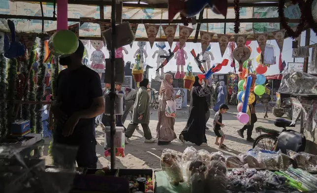 Palestinians walk past a toys shop at a market ahead of the Muslim holiday of Eid Al Adha, in Khan Younis, Gaza, Wednesday, June 4, 2025. (AP Photo/Abdel Kareem Hana)