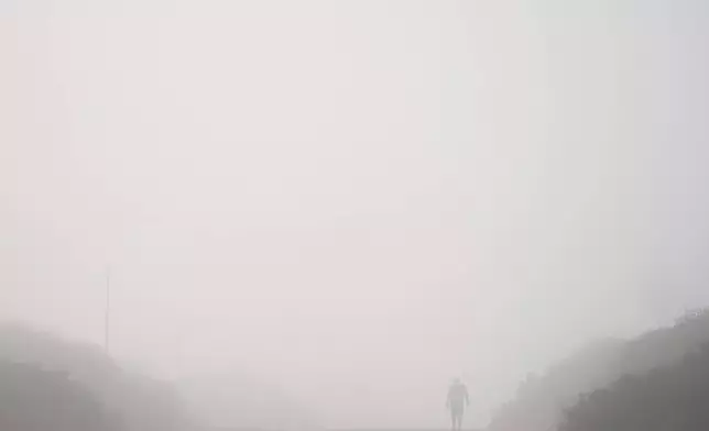 A man walks as fog covers Orot Rabin power plant near Hadera, Israel, Friday, June 6, 2025. (AP Photo/Ariel Schalit)