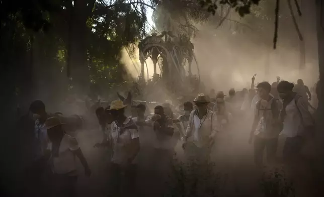 Pilgrims walk through dusty terrain, on their way to the shrine of El Rocio near Aznalcázar, Spain, on Friday, June 6, 2025, during the annual pilgrimage in which hundreds of thousands of devotees of the Virgin del Rocio converge in and around the shrine. (AP Photo/Emilio Morenatti)