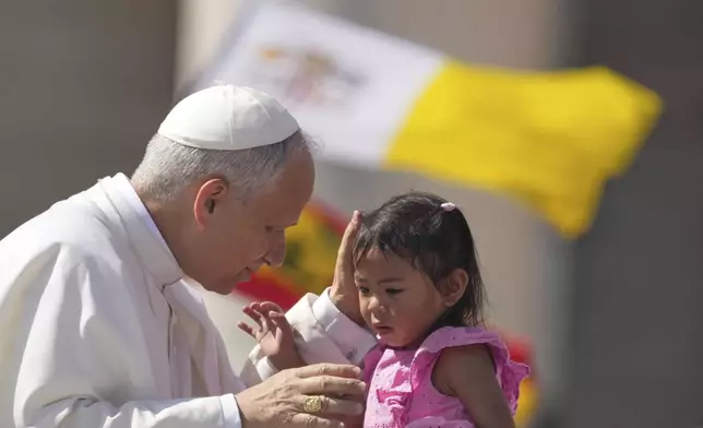 Pope Leo XIV caresses a little girl as he arrives to celebrate a Mass for the Jubilee of New Religious Associations on Pentecost Day in St. Peter's Square at the Vatican, Sunday, June 8, 2025. (AP Photo/Andrew Medichini)