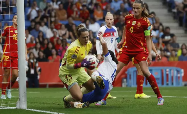 Spain goalkeeper Catalina Coll makes a save in front of England's Jessica Carter during the women's Nations League soccer match between Spain and England at the RCD Espanyol Stadium, in Barcelona, Spain, Tuesday, June 3, 2025. (AP Photo/Joan Monfort)