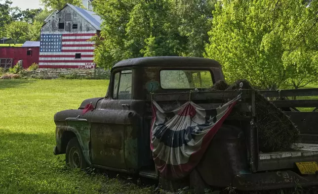 A flag-painted barn stands in the distance beyond an old pickup truck Saturday, June 7, 2025, on the a farm owned by Quentin and Karrie Brewer near Loring, Kan. The barn was painted by Quentin, who's birthday is flag day, with 38 stars representing the number of states in the union when the barn was built in 1884. (AP Photo/Charlie Riedel)