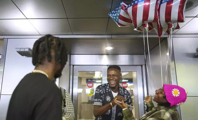 Key Felix, center, of Haiti, is greeted by his sister, carrying American flag balloons, as he arrives in Miami for his first visit to the U.S., at Miami International Airport, Monday, June 9, 2025. (AP Photo/Rebecca Blackwell)