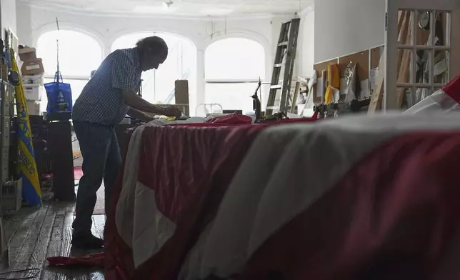 Tim O'Connor works on a large United States flag at Humphrys Flag Company that will be draped outside their building for Flag Day, in Philadelphia, Tuesday, June 10, 2025. (AP Photo/Matt Rourke)