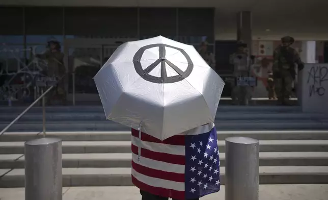 A protester stands in front of a line of law enforcement personnel at a Federal Building on Monday, June 9, 2025, in downtown Los Angeles. (AP Photo/Eric Thayer)