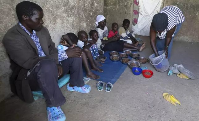 Aujene Cimanimpaye, from the Democratic Republic of Congo, gives food to her family at the Kakuma Refugee Camp in Turkana County, Kenya, Wednesday, June 4, 2025. (AP Photo/Andrew Kasuku)