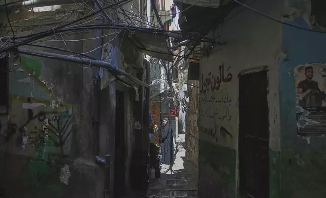 A woman walks through a narrow alley in the Mar Elias refugee camp in Beirut, Lebanon, Monday, June 2, 2025. (AP Photo/Hassan Ammar)