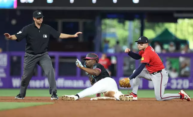 Miami Marlins' Jesus Sanchez, center, safely slides into second base during the third inning of a baseball game against the Atlanta Braves, Saturday, June 21, 2025, in Miami. (AP Photo/Alexandra Rodriguez)