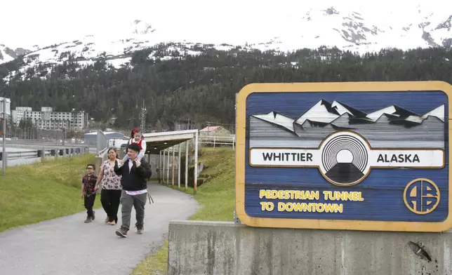Michael Pese, with daughter Cataleya on his shoulders, and his wife, Tupe Smith, with their son Maximus exit a pedestrian tunnel underneath Whittier, Alaska, May 13, 2025. (AP Photo/Mark Thiessen)