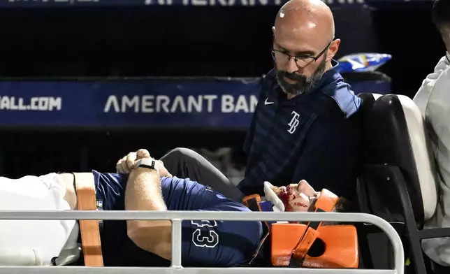 Tampa Bay Rays' Hunter Bigge is taken off the field after being hit by a foul ball while in the dugout during the seventh inning of a baseball game against the Baltimore Orioles, Thursday, June 19, 2025, in Tampa, Fla. (AP Photo/Jason Behnken)