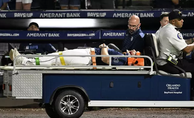 Tampa Bay Rays' Hunter Bigge is taken off the field after being hit by a foul ball while in the dugout during the seventh inning of a baseball game against the Baltimore Orioles, Thursday, June 19, 2025, in Tampa, Fla. (AP Photo/Jason Behnken)