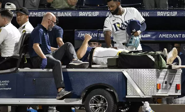 Tampa Bay Rays' Junior Caminero, right, stands teammate with Hunter Bigge as Bigge is taken off the field after being hit by a foul ball while in the dugout during the seventh inning of a baseball game against the Baltimore Orioles, Thursday, June 19, 2025, in Tampa, Fla. (AP Photo/Jason Behnken)