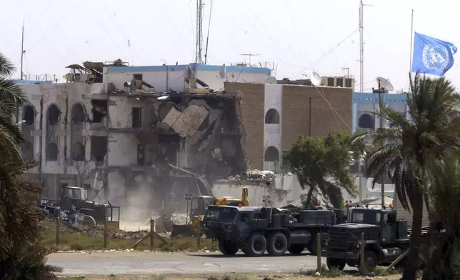 FILE - U.S. military vehicles pass the collapsed section of the United Nations headquarters Saturday, Aug. 23, 2003, in Baghdad, Iraq. (AP Photo/Manish Swarup, File)