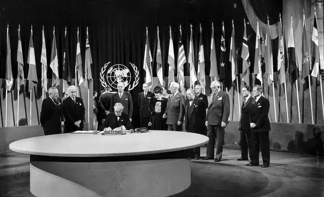 FILE - President Harry S. Truman and the entire American delegation watch as Sen. Tom Connally signs the United Nations Charter in San Francisco, June 26, 1945. Standing, from left, after Truman are Secretary of State Edward Stettinius Jr.; Harold Edward Stassen; unidentified; Dean Virginia Gildersleeve; Rep. Charles A. Eaton; Rep. Sol Bloom, and Sen. Arthur Vandenberg. (AP Photo, File)
