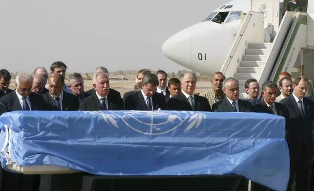 FILE - U.S. administrator in Iraq Paul Bremer, fourth left, along with UN and Iraqi officials pays last respects before Sergio Vieira de Mello's coffin, draped in a UN flag is loaded on a Brazilian presidential plane at Baghdad international airport, in Baghdad, Iraq, Aug. 22, 2003. Vieira de Mello, the top U.N. official in Iraq, was killed in a suicide truck bombing attack on U.N. headquarters that killed at least 22 other people and left more than 100 injured. (AP Photo/Manish Swarup, File)