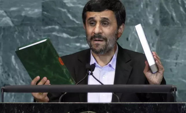 FILE - Iran's President Mahmoud Ahmadinejad, President of Iran, holds up a copies of the Quran, left, and Bible, right, as he addresses the 65th session of the United Nations General Assembly at U.N. headquarters, Sept. 23, 2010, during a speech where he prompted walkouts from the assembly when he questioned whether the Sept. 11 attacks were staged. (AP Photo/Richard Drew, File)