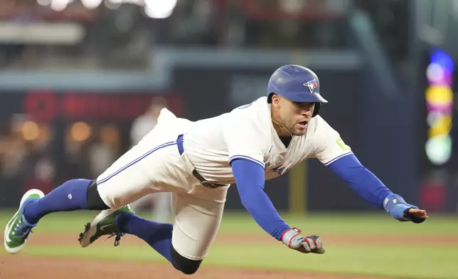 Toronto Blue Jays' George Springer (4) dives into third base before scoring on a hit by Ernie Clement following a throwing error by Chicago White Sox outfielder Austin Slater during the second inning of a baseball game, Saturday June 21, 2025, in Toronto. (Chris Young/The Canadian Press via AP)