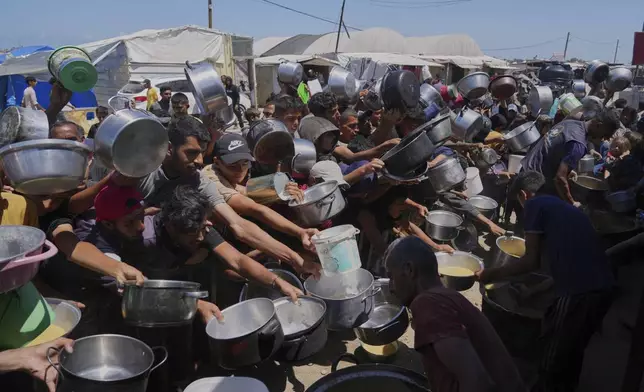 Palestinians struggle to get donated food at a community kitchen in Khan Younis, southern Gaza Strip, Monday, June 2, 2025. (AP Photo/Abdel Kareem Hana)