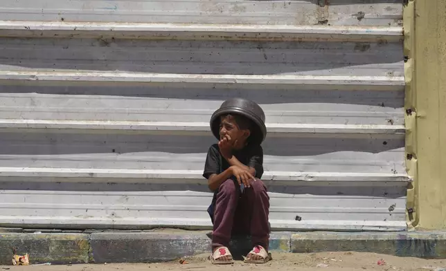 A Palestinian boy sits on the curb as he waits near a food distribution kitchen in Khan Younis, southern Gaza Strip, Monday, June 2, 2025. (AP Photo/Abdel Kareem Hana)