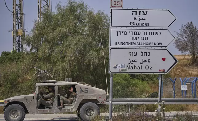 Israeli army vehicle pass by a new sign pointing towards Gaza reading "To release Omri Miron go straight" near Kibbutz Nahal Oz in southern Israel, where Miron was kidnapped from on Oct. 7, on Sunday, June 1, 2025. (AP Photo/Ohad Zwigenberg)