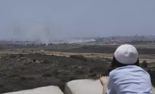 A child watches smoke from Israeli bombardment billowing over buildings in the northern Gaza Strip, from an overlook in Sderot, southern Israel on the Jewish holiday of Shavuot, Monday, June 2, 2025. (AP Photo/Maya Alleruzzo)