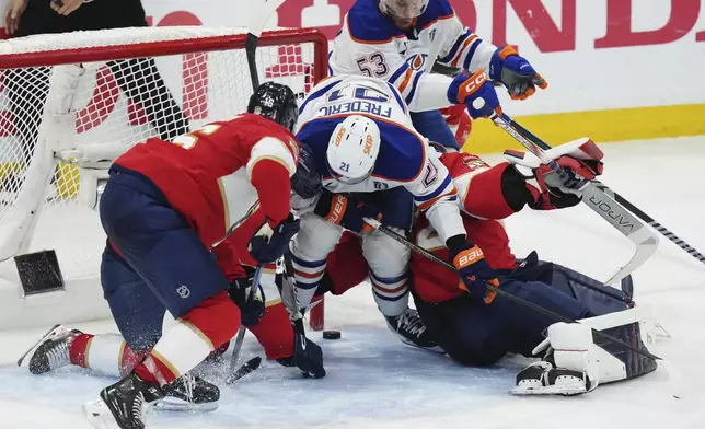 Florida Panthers goalie Sergei Bobrovsky, bottom right, makes a save against Edmonton Oilers' Trent Frederic (21) during the first overtime period in Game 4 of the NHL hockey Stanley Cup Final in Sunrise, Fla., Thursday, June 12, 2025. (Nathan Denette/The Canadian Press via AP)
