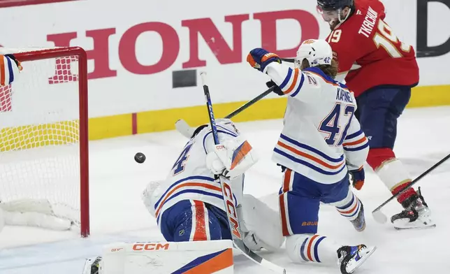Florida Panthers' Matthew Tkachuk (19) scores against Edmonton Oilers goalie Stuart Skinner, left, as Oilers'. Kasperi Kapanen (42) defends during the first period in Game 4 of the NHL hockey Stanley Cup Final in Sunrise, Fla., Thursday, June 12, 2025. (Nathan Denette/The Canadian Press via AP)