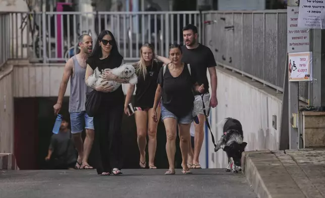 People leave an underground parking garage where they took shelter after an air raid alarm of Iranian missile attacks went off, in Tel Aviv, Israel, Tuesday, June 24, 2025. (AP Photo/Ohad Zwigenberg)