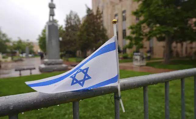The flag of Israel tops a makeshift memorial for victims of an attack outside of the Boulder County, Colo., courthouse as a light rain falls Tuesday, June 3, 2025, in Boulder, Colo. (AP Photo/David Zalubowski)