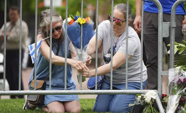 From left, Lisa Turnquist and Carrie Spyva-McIlvaine place a bouquet of flowers at a growing memorial outside of the Boulder County, Colo., courthouse after Sunday's attack Monday, June 2, 2025, in Boulder, Colo. (AP Photo/David Zalubowski)