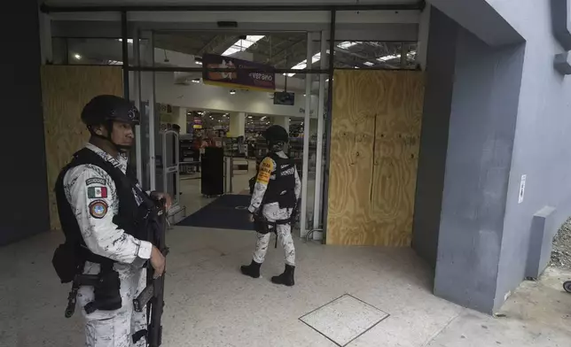 National Guards stand guard at the entrance to a grocery store on Manzanillo beach after Hurricane Erick hit near Acapulco, Mexico, Thursday, June 19, 2025. (AP Photo/Fernando Llano)