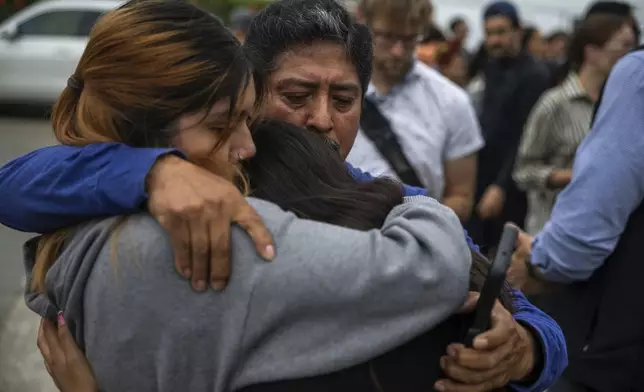 Jaslyn Hernandez, daughter of a car wash worker, embraces her sister Kimberly Hernandez, and their uncle Juan Medina during a press conference with families of detained car wash workers Wednesday, June 11, 2025, in Culver City, Calif. (AP Photo/Ethan Swope)