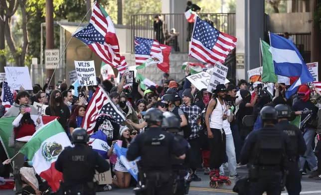 EDS NOTE: OBSCENITY - Law enforcement officers stand guard as demonstrators protest on Wednesday, June 11, 2025, in Los Angeles. (AP Photo/Ethan Swope)