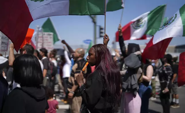 A protester cools down with an icicle while joining other protesters waving Mexican National Flags during a protest to denounce ICE, U.S. Immigration and Customs Enforcement, operations in the area Tuesday, June 10, 2025, in downtown Los Angeles. (AP Photo/Eric Thayer)