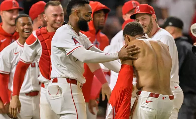 Los Angeles Angels' Christian Moore, shirtless, is congratulated by Angels' Jo Adell, left, and Angels' Taylor Ward after hitting a walk-off two-run home run in the tenth inning of a baseball game against the Boston Red Sox, Tuesday, June 24, 2025, in Anaheim, Calif. (AP Photo/Jayne Kamin-Oncea)