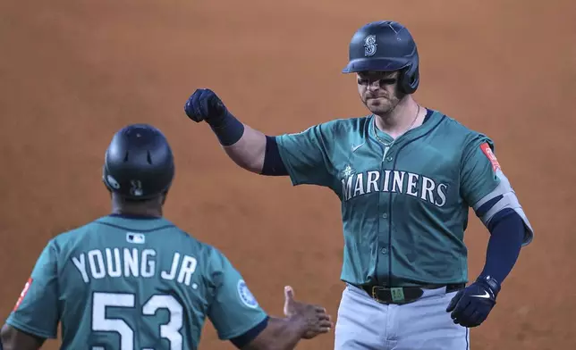 Seattle Mariners' Mitch Garver, right, celebrates with first base coach Eric Young Jr. (53) after hitting a run-scoring single in the sixth inning of a baseball game against the Texas Rangers, Sunday, June 29, 2025, in Arlington, Texas. (AP Photo/Tony Gutierrez)