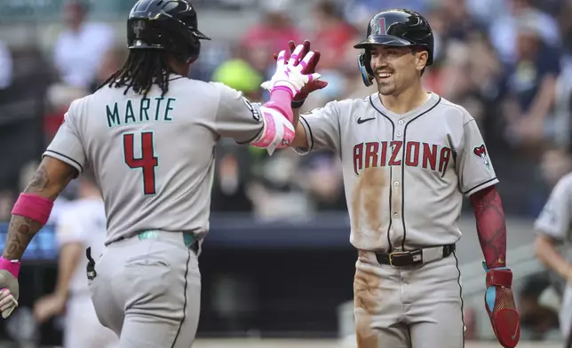 Arizona Diamondbacks' Ketel Marte (4) high-fives Corbin Carroll, right, after hitting a two-run home run in the third inning of a baseball game against the Atlanta Braves, Tuesday, June 3, 2025, in Atlanta. (AP Photo/Colin Hubbard)