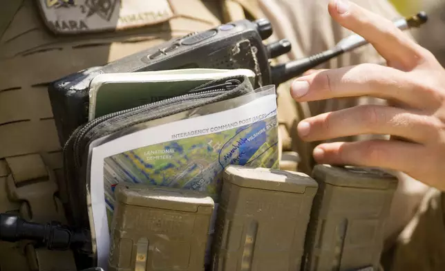 A U.S Marine adjusts their radio and outside of a federal building Friday, June 13, 2025, in Los Angeles (AP Photo/Noah Berger)