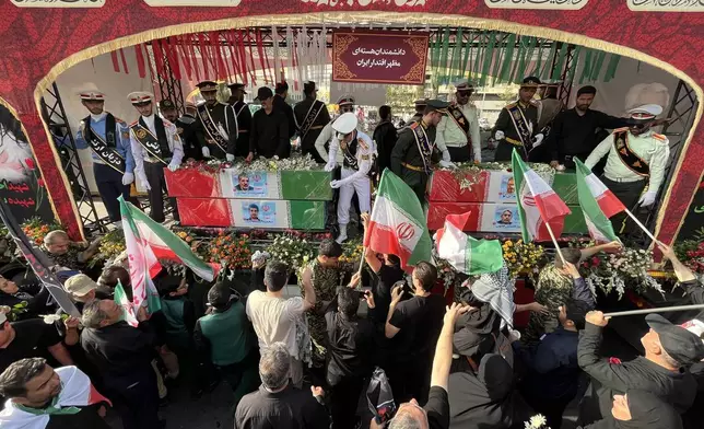 People mourn over the flag-draped coffins of Iranian nuclear scientists who were killed in Israeli strikes, during a funeral ceremony in Tehran. Iran, Saturday, June 28, 2025. (AP Photo/Vahid Salemi)