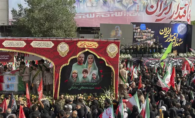 People mourn over the flag-draped coffins of Iranian army generals, nuclear scientists and their family members who were killed in Israeli strikes, during a funeral ceremony in Tehran. Iran, Saturday, June 28, 2025. (AP Photo/Vahid Salemi)