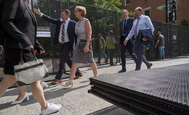 People walk by security fencing as it is installed around Lafayette Park and the White House during security preparations for a festival and parade to commemorate the 250th Birthday of the U.S. Army, Monday, June 9, 2025, in Washington. (AP Photo/Jacquelyn Martin)