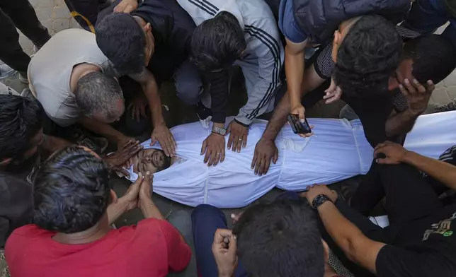 Relatives mourn over the body of Palestinian Bilal Abu Amsha, who was killed among others in Israeli strikes on the Gaza Strip, at Al-Shifa Hospital in Gaza City, Saturday, June 28, 2025. (AP Photo/Jehad Alshrafi)