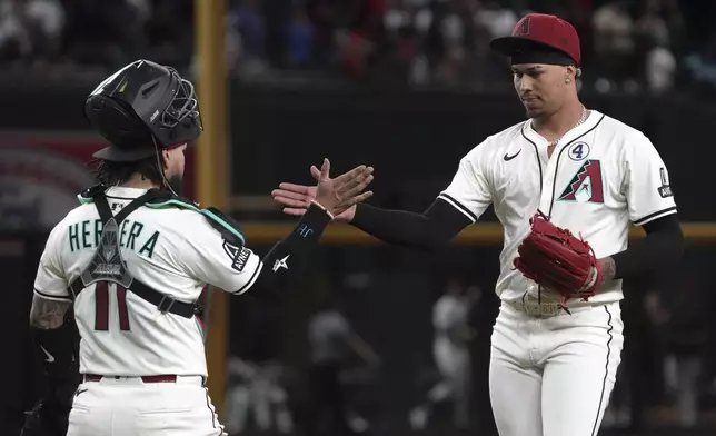 Arizona Diamondbacks catcher Jose Herrera (11) and pitcher Justin Martinez, right, celebrate after defeating the Washington Nationals in a baseball game, Sunday, June 1, 2025, in Phoenix. (AP Photo/Rick Scuteri)