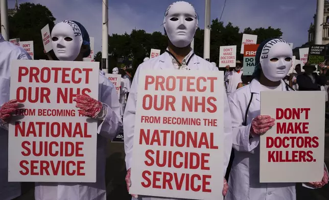 Demonstrators against assisted dying hold banners outside Parliament in London, Friday, June 20, 2025, as British lawmakers are set to vote Friday on whether to back a bill to help terminally ill adults end their lives in England and Wales. (AP Photo/Kirsty Wigglesworth)