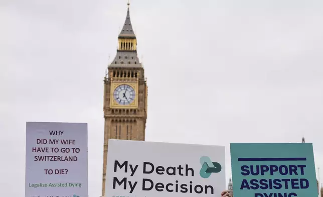 FILE -Banners are held by pro-assisted dying campaigners as they gather outside Parliament ahead of Fridays report stage in the Commons on The Terminally Ill Adults (End of Life) Bill which is expected to see MPs vote on further amendments, in Westminster in London, May 15, 2025. (AP Photo/Kirsty Wigglesworth, File)