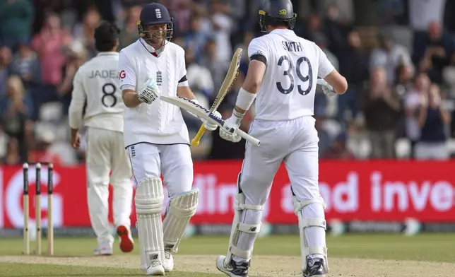 England's Jamie Smith, right, and batting partner Joe Root celebrate after their win on day five of the first cricket test match against India at Headingley in Leeds, England, Tuesday, June 24, 2025. (AP Photo/Scott Heppell)