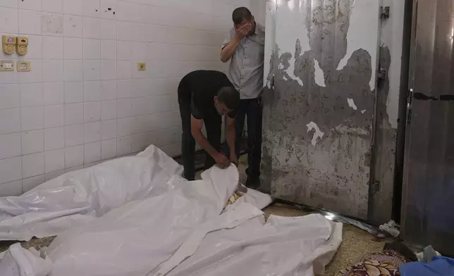Palestinians mourn over the bodies of people who were killed during an Israeli strike, at the morgue of Al-Aqsa Hospital in Deir al-Balah, Gaza Strip, Wednesday, June 25, 2025. (AP Photo/Abdel Kareem Hana)