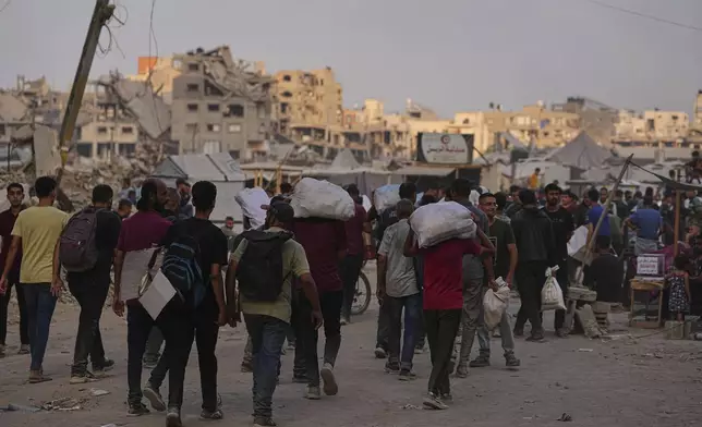 Palestinians carry sacks of food and humanitarian aid unloaded from trucks convoy that had been heading to Gaza City, in the northern Gaza Strip, Sunday, June 22, 2025. (AP Photo/Jehad Alshrafi)