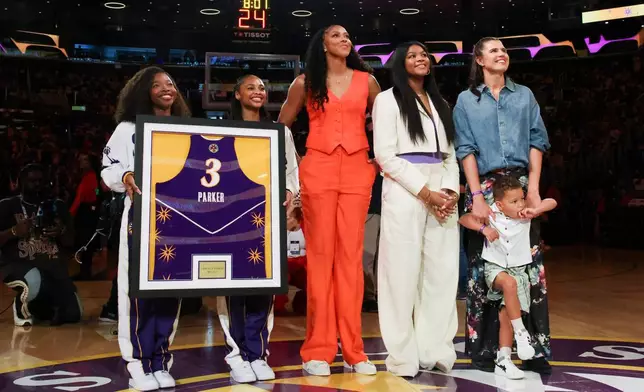 The jersey of former Los Angeles Sparks player Candace Parker, center, looks on with her family during her jersey retirement ceremony during a WNBA basketball game between the Sparks and the Chicago Sky, Sunday, June 29, 2025, in Los Angeles. (AP Photo/Jessie Alcheh)